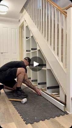 a man kneeling down on the floor in front of a stair case