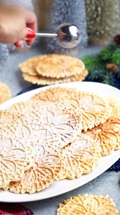 a person is sprinkling sugar on some crackers with a spoon in front of them