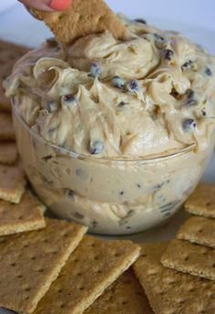 a cracker dipping some food into a bowl filled with cream cheese and chocolate chips