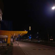 an empty street at night with the lights turned on and no cars parked in front