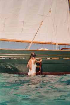 a woman standing in the water next to a boat