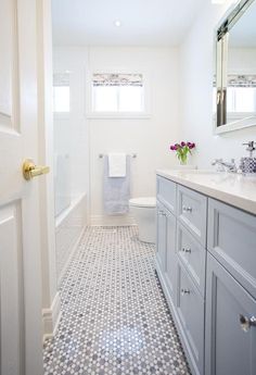 a bathroom with white walls and gray cabinets