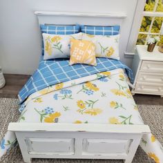 a white bed with yellow and blue flowers on the comforter, pillows and pillow cases