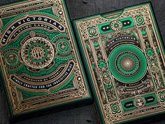 two green and gold playing cards sitting on top of a wooden table next to each other