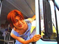 a woman with red hair leaning out the window of a bus