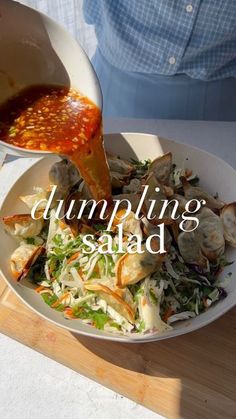 a person pouring sauce over a salad in a bowl