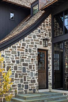 a stone building with a wooden door and window frames on the side of it's front porch