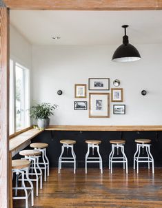 an empty bar with stools and pictures on the wall