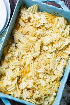 a blue casserole dish filled with macaroni and cheese on a wooden table