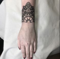 a woman's hand with a black and white tattoo design on her left wrist