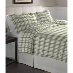 a bed with green and white plaid bedspread on top of it, next to a night stand