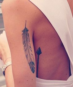 the back of a woman's white dress with an arrow tattoo