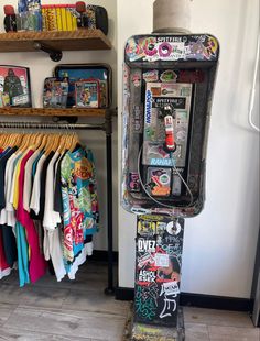 a vending machine sitting inside of a store next to a shelf filled with t - shirts