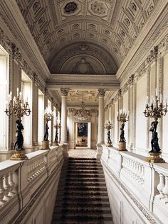 an ornate hallway with chandeliers and marble steps leading up to the second floor