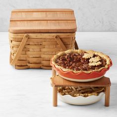 three pies stacked on top of each other in front of a wooden box and basket