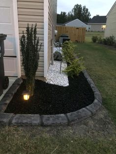 a small garden area with gravel and lights in the grass, next to a house