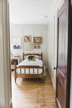 a bed sitting in the middle of a bedroom next to a wooden door with pictures on it