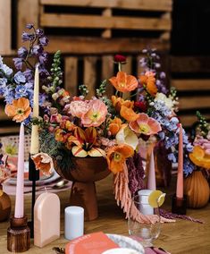 an arrangement of flowers and candles on a table