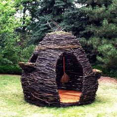 a small house made out of branches in the grass