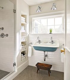 a bathroom with a sink, mirror and shower in it's corner next to a window