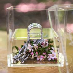 a small glass box with flowers inside on a wooden table next to a pair of scissors