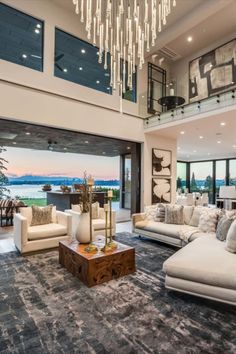 a living room filled with lots of furniture and a chandelier hanging from the ceiling