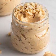 two jars filled with peanut butter on top of a table