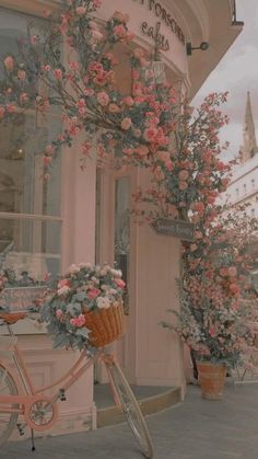 a pink bicycle parked in front of a building with flowers growing on it's side