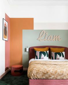 a bed with two pillows on top of it next to a wall painted in different colors