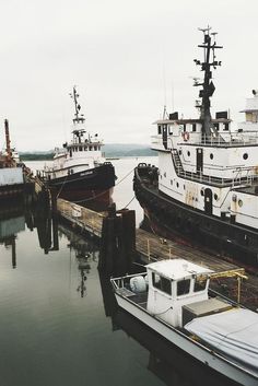 two boats are docked next to each other in the water near another boat on land