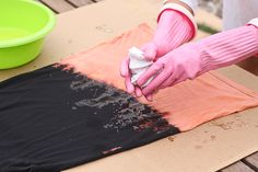 a person in pink gloves and white shirt wiping up an orange piece of cloth on top of a table