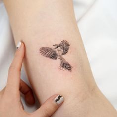 a woman's arm with a small tattoo of a bird on the left side