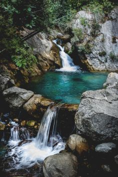 there is a small waterfall in the middle of some rocks and water that runs down it