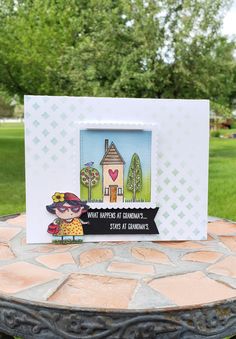 a card with a house on it sitting on top of a table in the grass