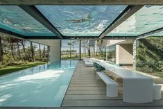 an indoor swimming pool in the middle of a house with glass walls and floor to ceiling windows