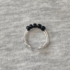 a black beaded ring sitting on top of a gray sweater