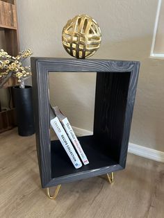 a book shelf with two books on it and a gold ball in the corner next to it