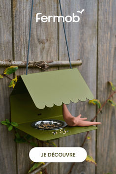 a bird feeder hanging from the side of a wooden fence with text overlay that reads fermob je decouvre