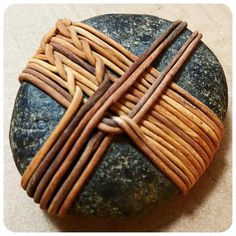 a cross made out of wood and wire sitting on top of a rock with a stone underneath it