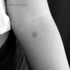 a small apple tattoo on the left inner arm, with an apple in it's center