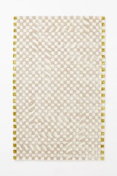 a white and yellow rug with gold trims on the edges, in front of a white background