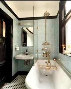 a bath tub sitting next to a sink under a window in a bathroom with black and white tiles