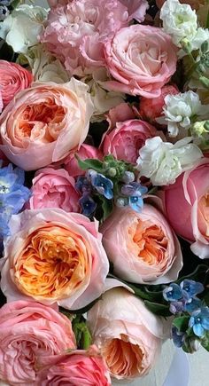 a white vase filled with lots of pink and blue flowers