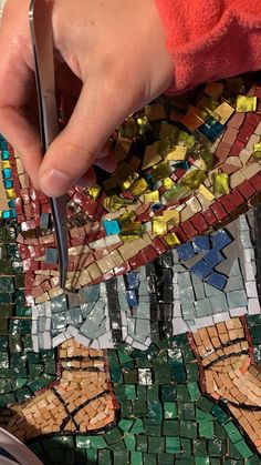 a person using scissors to cut up mosaic tiles