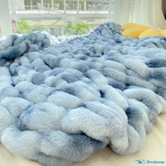 a blue blanket is laying on top of a bed with yellow pillows in the background