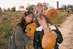 three young women holding pumpkins in their hands