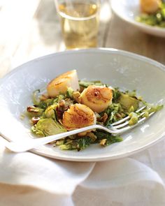 a white plate topped with scallops and broccoli on top of a table