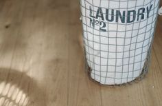 a white cup sitting on top of a wooden table next to a metal wire basket