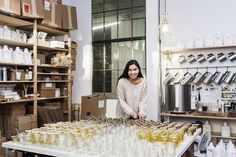 a woman standing behind a table filled with lots of bottles