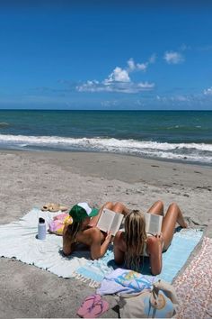 a woman laying on top of a beach next to the ocean